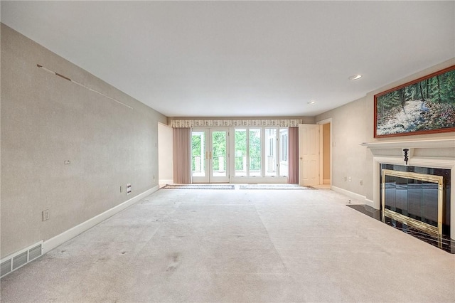 unfurnished living room with carpet floors, a fireplace with flush hearth, baseboards, and recessed lighting
