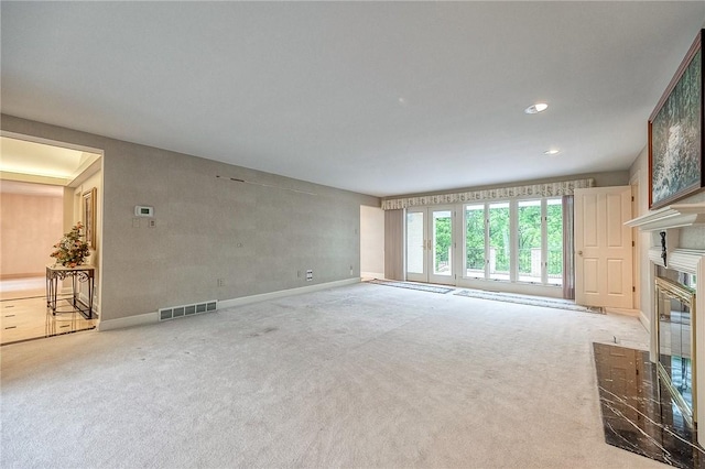 unfurnished living room featuring carpet flooring, a glass covered fireplace, baseboards, and recessed lighting