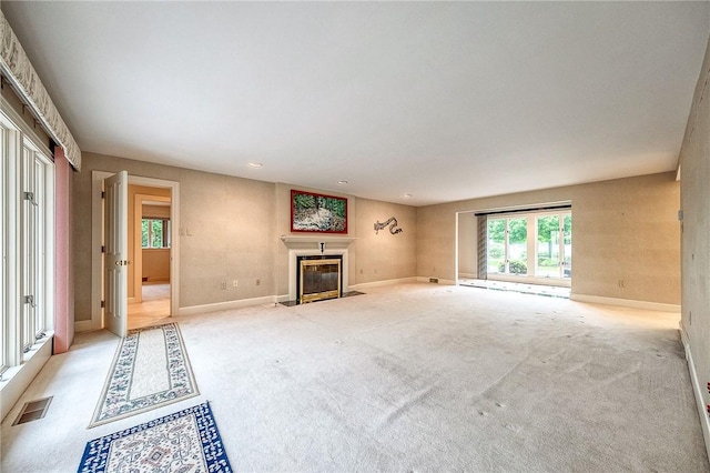 unfurnished living room with a fireplace with flush hearth, light carpet, baseboards, and recessed lighting