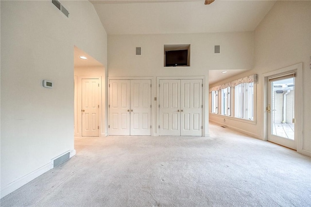 unfurnished bedroom with high vaulted ceiling, carpet floors, two closets, access to outside, and baseboards