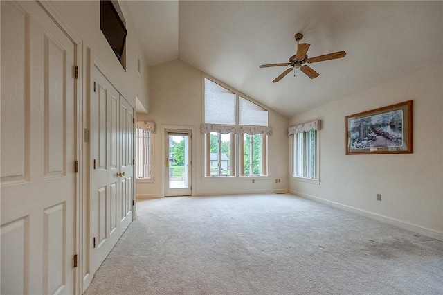 empty room featuring ceiling fan, light colored carpet, baseboards, and high vaulted ceiling