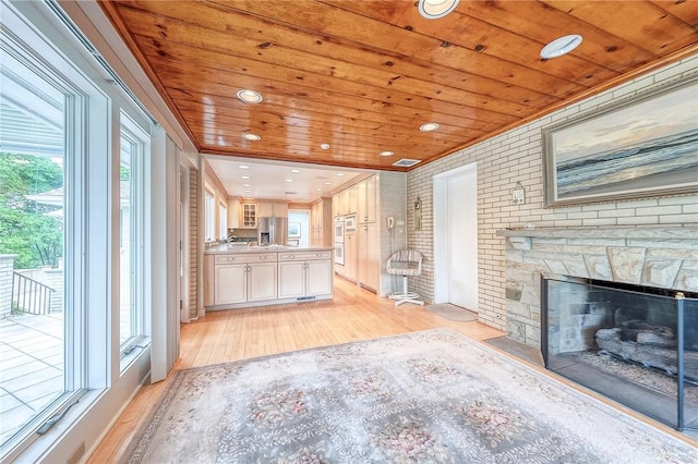 unfurnished living room featuring brick wall, light wood-type flooring, wood ceiling, a fireplace, and ornamental molding