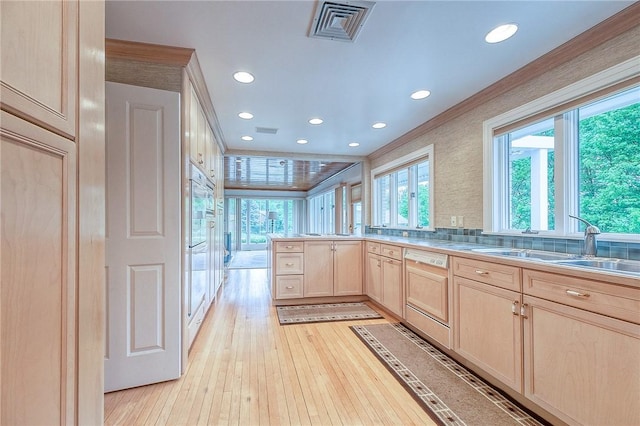 kitchen featuring light brown cabinets, crown molding, recessed lighting, a peninsula, and a sink