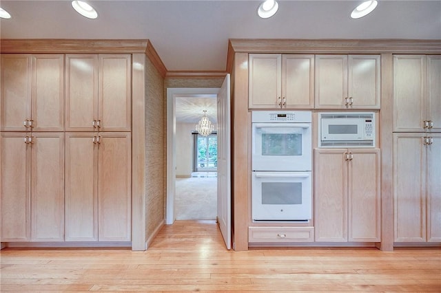 kitchen featuring white appliances, light brown cabinetry, light wood-style floors, a chandelier, and baseboards