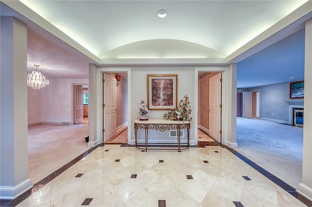 hall featuring inlaid floor details, a chandelier, baseboards, a tray ceiling, and recessed lighting