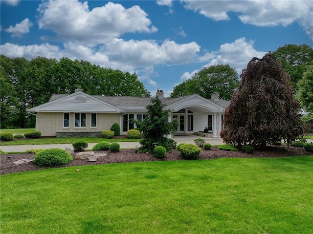 ranch-style house with a front yard, brick siding, and a chimney