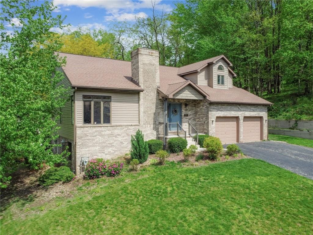 263 Arbor Hill Rd, Hempfield Twp Wml, PA 15601 - view of front of house with driveway, a chimney, brick siding, an attached garage, and roof with shingles