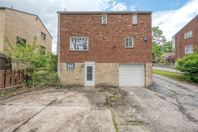 1593 Riverside Dr, Penn Hills, PA 15147 - rear view of house featuring driveway, an attached garage, brick siding, and fence