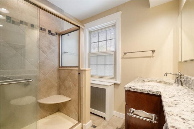 full bathroom with a stall shower, vanity, tile patterned flooring, and baseboards