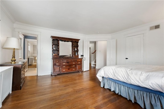 bedroom with wood finished floors and crown molding