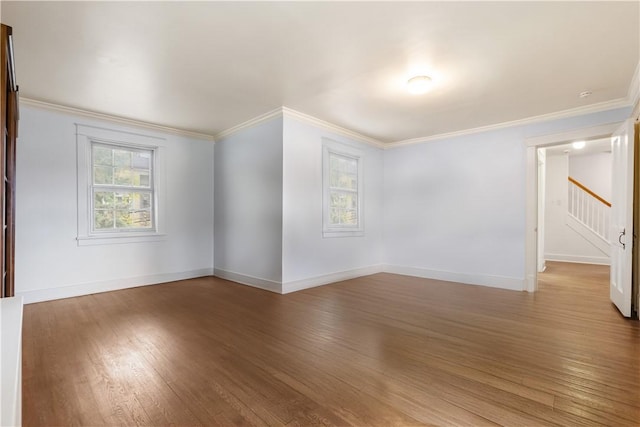 spare room featuring wood finished floors, ornamental molding, baseboards, and stairs