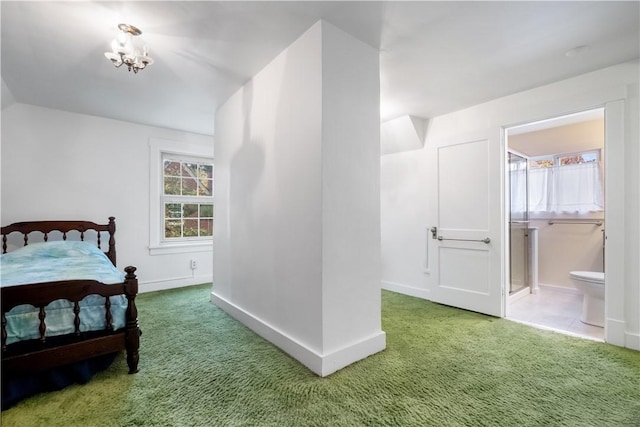 carpeted bedroom with ensuite bathroom, a chandelier, and baseboards