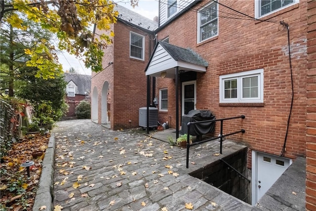 back of property featuring central AC and brick siding