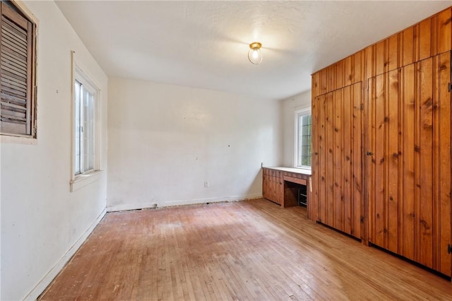 unfurnished bedroom with light wood-type flooring, multiple windows, and baseboards