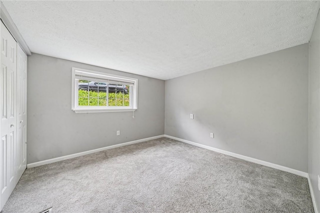 unfurnished bedroom featuring a textured ceiling, carpet, a closet, and baseboards