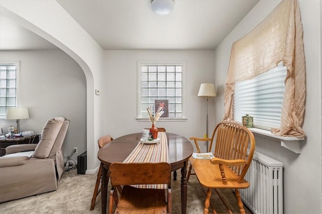 carpeted dining area with arched walkways and healthy amount of natural light