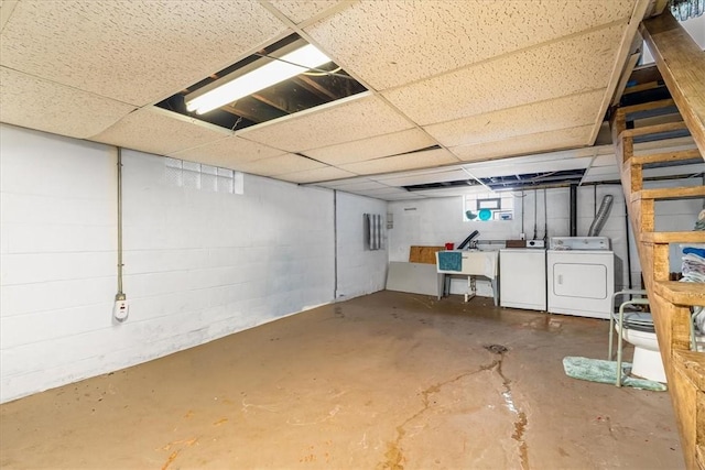 basement featuring washer and clothes dryer, a drop ceiling, and a sink