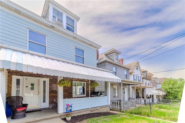 view of front of house featuring fence, a porch, metal roof, and a residential view
