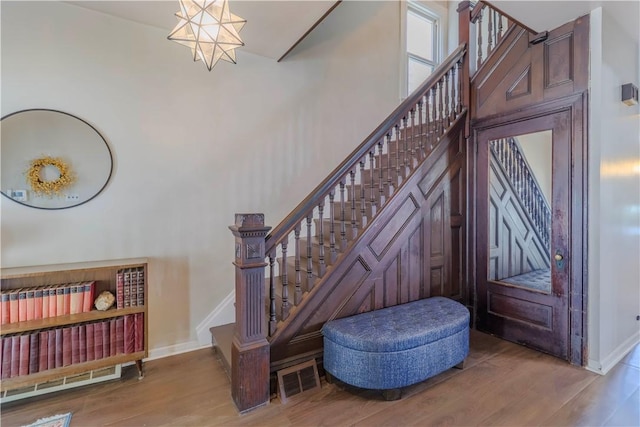 staircase with wood finished floors, baseboards, and a towering ceiling