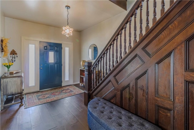 foyer featuring dark wood-style floors, stairs, and a chandelier