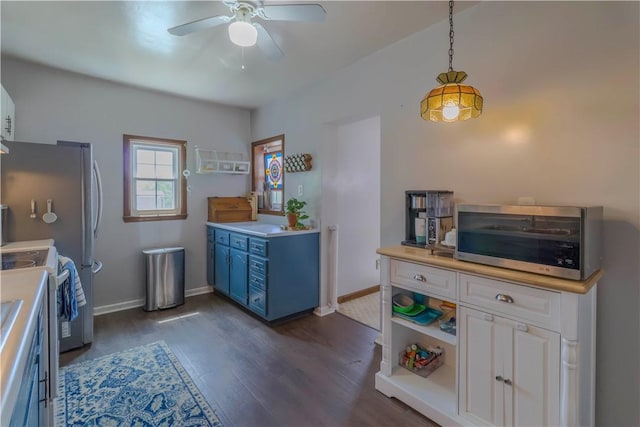 kitchen with blue cabinetry, ceiling fan, stainless steel microwave, light countertops, and dark wood finished floors
