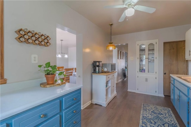 kitchen featuring blue cabinetry, light countertops, dark wood-style flooring, ceiling fan, and decorative light fixtures