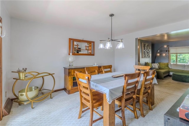 dining room with light carpet and a chandelier