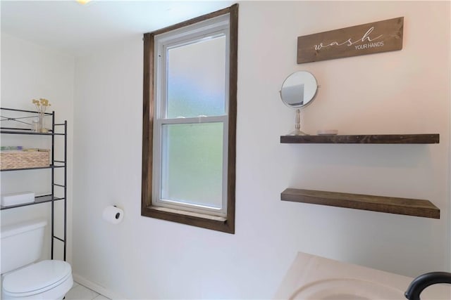bathroom with toilet, a sink, and baseboards