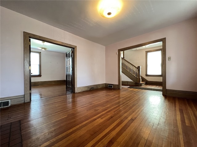 unfurnished room with dark wood-type flooring, stairs, and baseboards