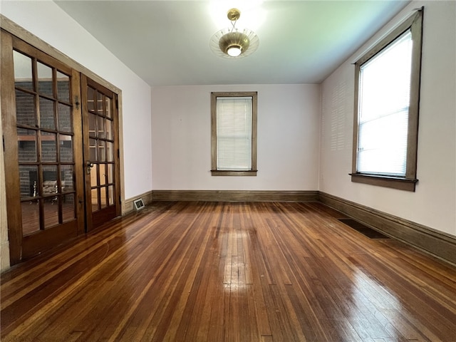 empty room featuring dark wood-type flooring, baseboards, and french doors