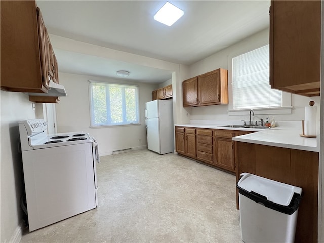 kitchen with white appliances, a sink, brown cabinetry, and baseboards