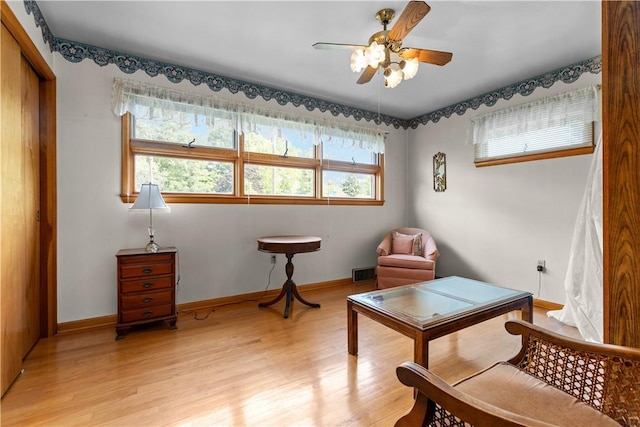 sitting room with light wood-style flooring, a ceiling fan, and baseboards