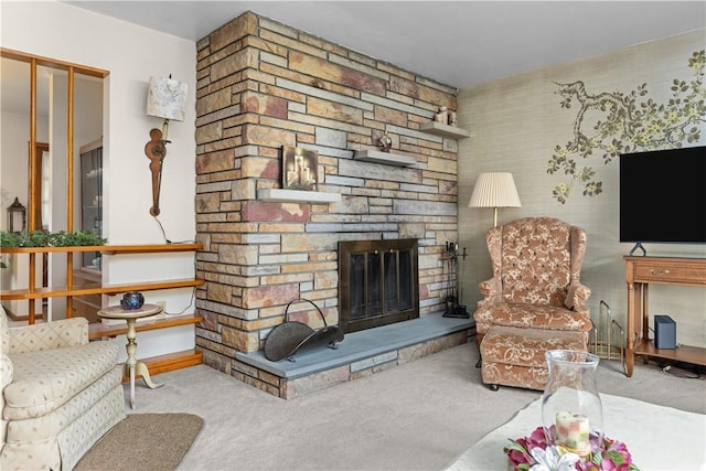 carpeted living room with a stone fireplace and baseboards