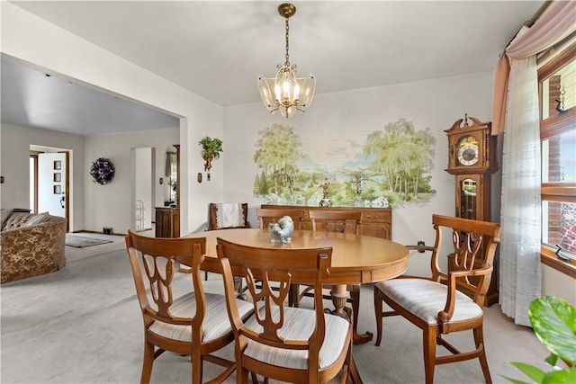 dining room featuring light carpet and a chandelier