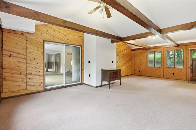 unfurnished living room featuring wood walls, carpet flooring, ceiling fan, and baseboards