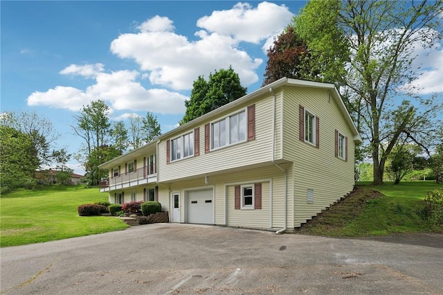 multi unit property featuring an attached garage, asphalt driveway, and a front lawn