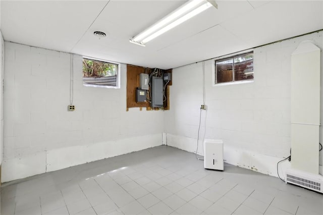 basement featuring concrete block wall, electric panel, and tile patterned flooring