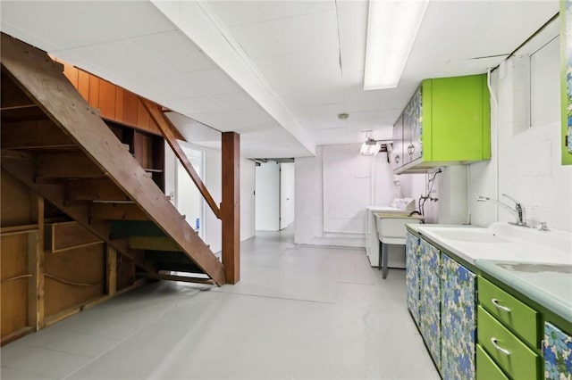 kitchen featuring a sink, washer / clothes dryer, light countertops, and finished concrete flooring