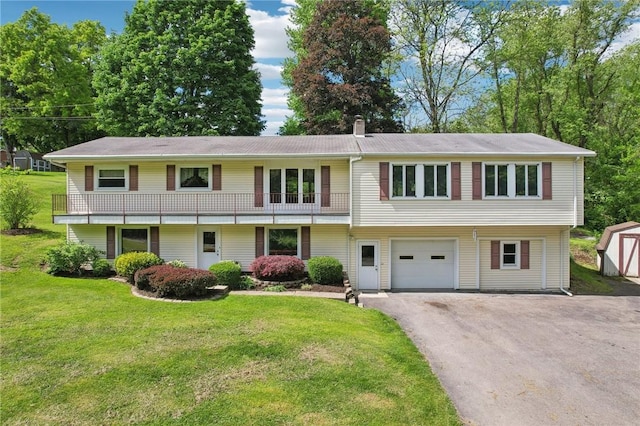 view of front of property featuring driveway, a front lawn, an attached garage, and a shed