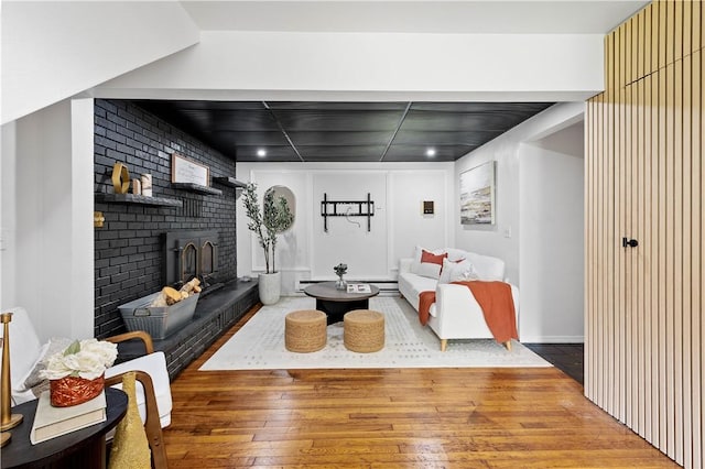 living room with hardwood / wood-style flooring, a brick fireplace, and brick wall