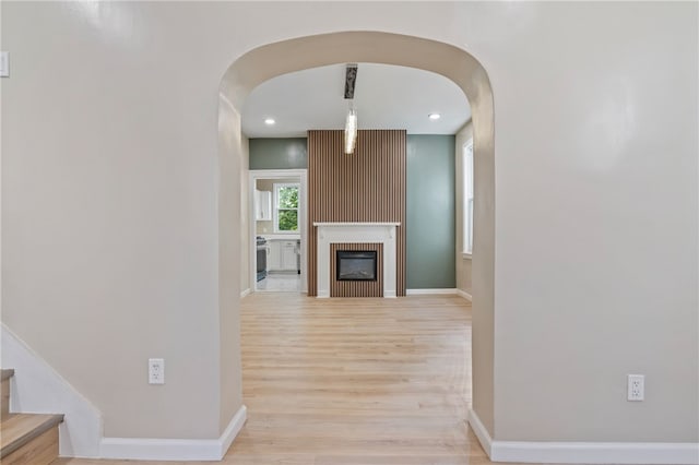 hallway with arched walkways, wood finished floors, baseboards, stairway, and recessed lighting