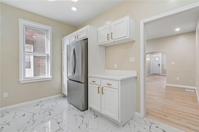 kitchen with freestanding refrigerator, arched walkways, baseboards, recessed lighting, and white cabinetry