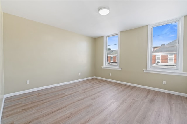 spare room with light wood-type flooring, healthy amount of natural light, and baseboards