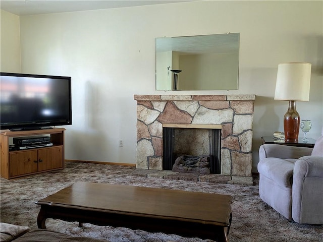 carpeted living area with a stone fireplace and baseboards