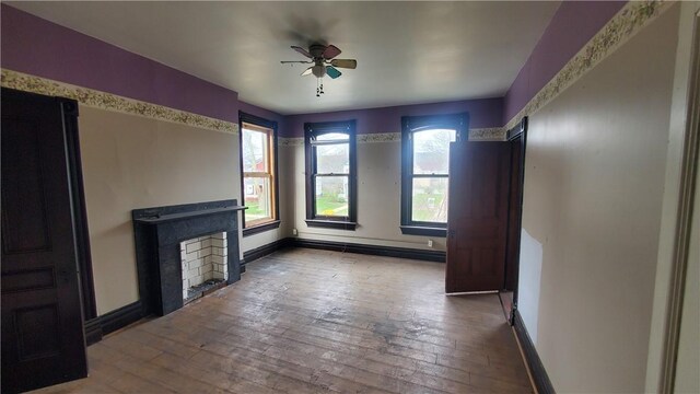 unfurnished living room featuring ceiling fan, wood-type flooring, and baseboards