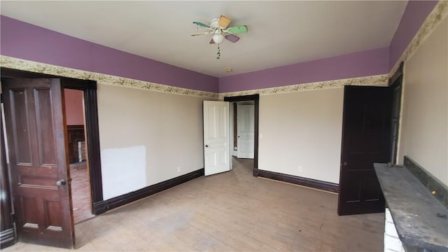 unfurnished bedroom with wood finished floors, baseboards, and a ceiling fan