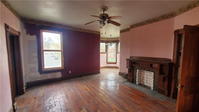 unfurnished living room featuring ceiling fan, healthy amount of natural light, hardwood / wood-style flooring, and baseboards