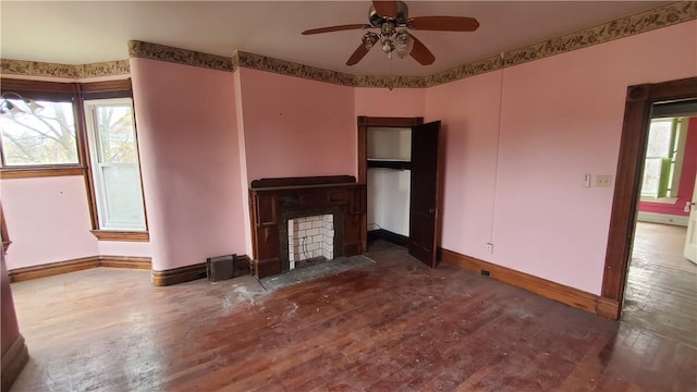 unfurnished living room featuring hardwood / wood-style flooring, baseboards, a ceiling fan, and a fireplace with flush hearth