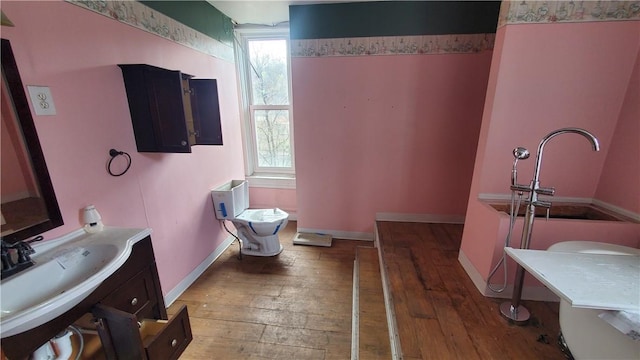 bathroom with hardwood / wood-style floors, baseboards, vanity, and toilet
