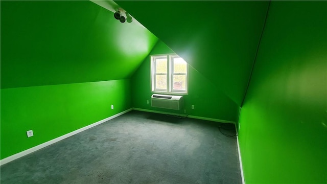 additional living space featuring a wall mounted AC, baseboards, lofted ceiling, and dark colored carpet